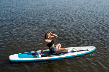Naklejka premium Young attractive woman posing on paddle board