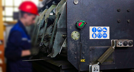 worker adjusts a punching machine at a factory.