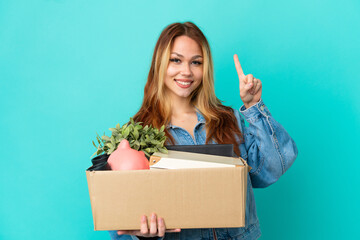 Teenager blonde girl making a move while picking up a box full of things pointing up a great idea