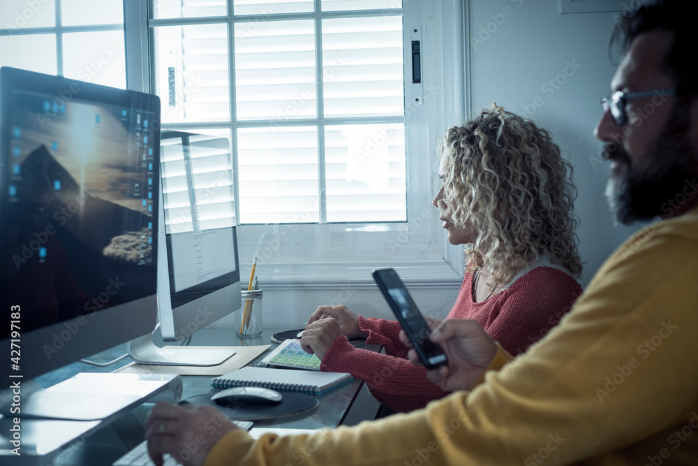 Wall mural adult caucasian couple at home in smart working and remote work job activity sitting at the desk in 