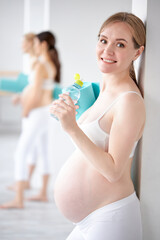 portrait of blonde caucasian pregnant female drinking water