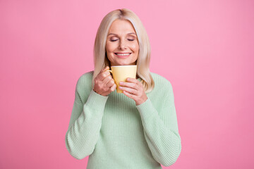 Photo portrait of old lady inhaling aroma of fresh coffee from yellow cup isolated on pastel pink...