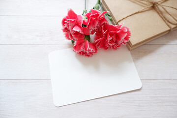 Empty greeting card set with carnation flowers and on wooden background. Mother’s Day, Father’s Day. ウッドテーブルを背景に手紙セットとピンクカーネーション、母の日、グリーティング