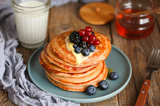 Breakfast.Macro delicious pancakes with fresh blueberries and maple syrup
Image shows a homemade fluffy pancake with blueberries on top.American breakfast with milk, honey.Vegetarian dish.World food 