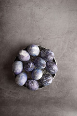 organic Easter eggs, hand-painted with natural blueberries, lie on a stone table. Easter concept. flat lay