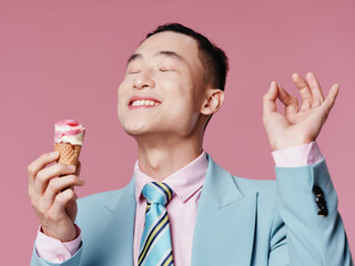 A man of Asian appearance is tasting gesticulating with his hands ice cream pink background model