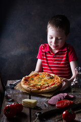 Kid cooked hot round pizza, puts on the table