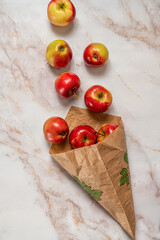 Fresh  red apples in a brown paper bag on a white marble  background.Top view..