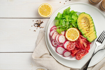 Healthy, vitamin-rich, diet salad with avocado, radish and tomatoes on a white wooden table. Summer recipes.