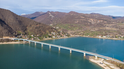 Aerial drone view of beautiful green lake, hills and villages. Huge Bridge over the river. Landscape.