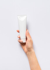 Beauty concept with woman hand and cream tube on lilac background