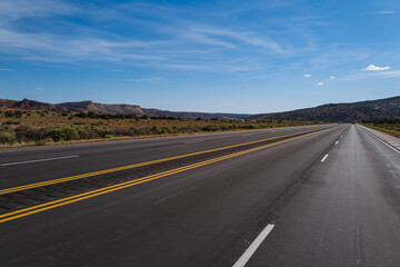 Fototapeta na wymiar Classic panorama view of an endless straight road running through the barren scenery of the American Southwest.