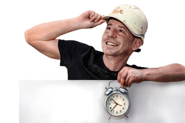 A man in a construction helmet holds on to it with one hand. An alarm clock is in the other hand....