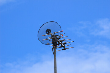 a television antenna against a beautiful backdrop of blue sky and clouds.
