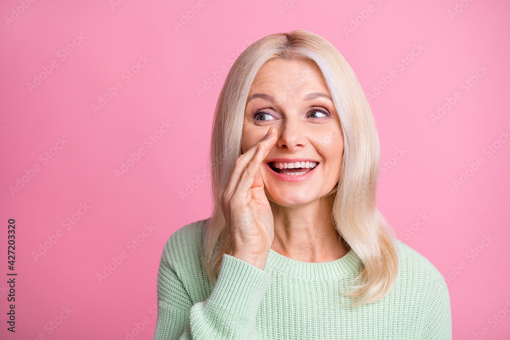 Sticker photo portrait of whispering old lady covering mouth with hand isolated on pastel pink colored backg