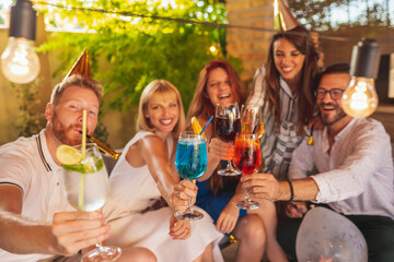 Friends making a toast with colorful cocktails at a birthday party