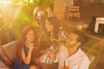 People blowing party whistles while having a surprise birthday party