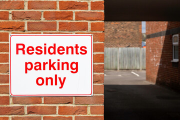 A Sign on the wall of an apartment block stating residents parking only