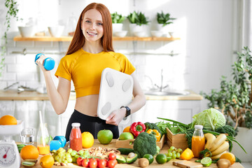 charming female with natural beauty and red hair smiling, standing with weight scales