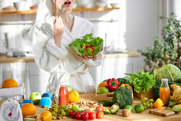 healthy young female in bathrobe enjoy making and eating fresh salad from vegetables