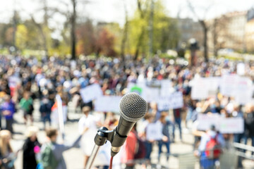Protest or public demonstration, focus on microphone, blurred group of people in the background