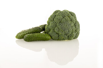 Cucumbers and broccoli lie on white glass on a white background