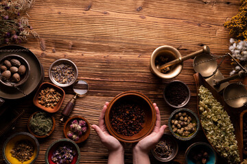 Natural medicine background. Preparation of herbs composition. Assorted dry herbs in bowls and brass mortar on rustic wooden table.
