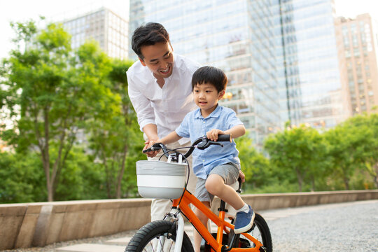 Happy young father teaching son to ride bike