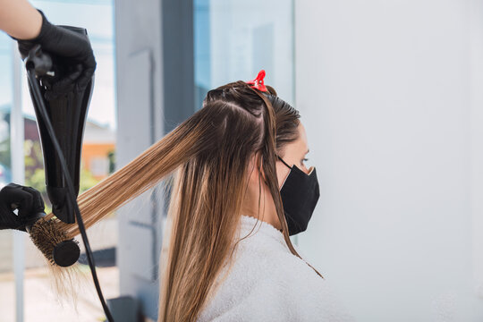 Hairdresser using a hairdryer on long hair in the beauty salon. - Powered by Adobe