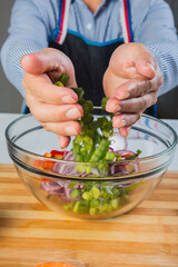 Close-up of hands putting green onions in a bowl.