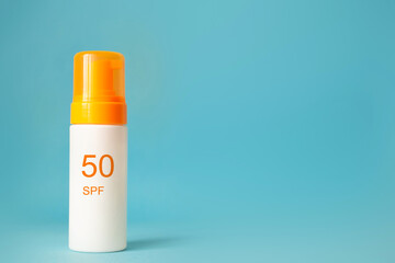 Sunscreen bottle with spf 50 cream or lotion on the aqua blue background with copy space. Sun protection, summer skin moisturizer