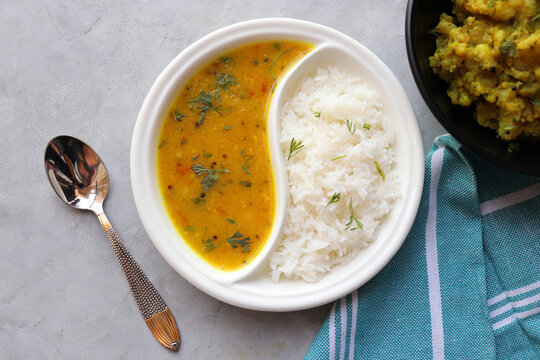 Healthy nutritious Indian comfort food Dal Chawal thali or Dal Rice, also commonly known as Varan bhat in Marathi. Served in two way ceramic plate. Over white background with copy space.