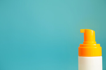 White and yellow sunscreen bottle with cream or lotion on the aqua blue background with copy space closeup. Spf sun protection, summer skin moisturizer