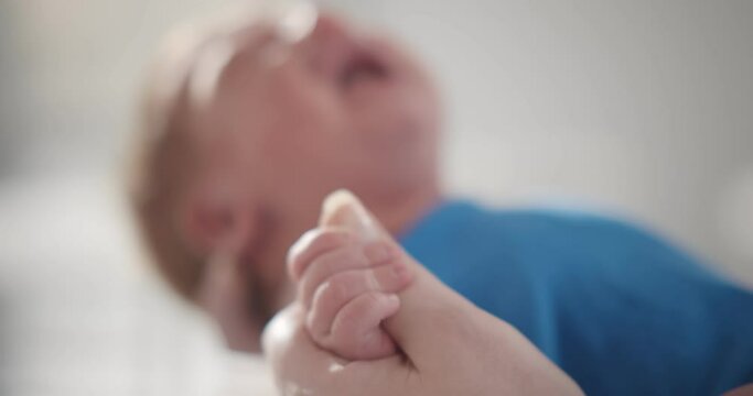 Focus on baby boy tinny hand holding mother finger