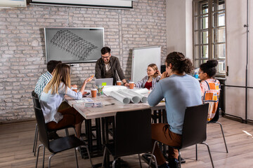 Group of young people discussing architectural designs in the creative office.