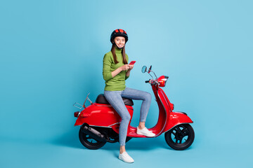 Fototapeta na wymiar Full length portrait of charming cheerful girl sitting moped look camera isolated on blue color background