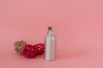 Metallic spray bottle with decorative balls on pink background