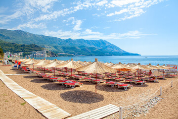 Becici beach in Montenegro , Sun umbrellas and loungers at the sandy beach . Summer Adriatic seaside