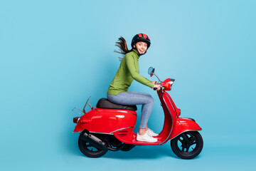Fototapeta na wymiar Full length photo portrait of excited girl in helmet driving red scooter isolated on pastel blue colored background