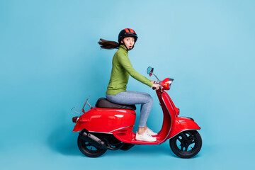 Profile side view portrait of attractive amazed cheerful girl riding moped pout lips way isolated over bright blue color background © deagreez