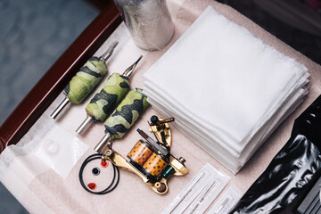 A set of tools for a tattoo artist. A layout of needles, napkins, a tattoo machine, replaceable...