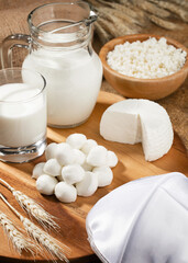 Different white cheese on wooden stand and spikelets of wheat.Concept for Shavuot holiday.