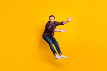 Fototapeta na wymiar Full length body size photo of man jumping flying back while windy storm isolated on vibrant yellow color background