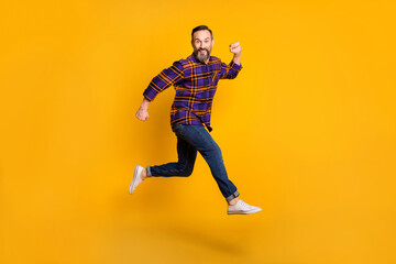 Fototapeta na wymiar Full length body size photo of man jumping high smiling in checkered shirt isolated on vivid yellow color background
