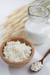 Cottage cheese  with milk and wooden spoon on white background...