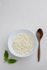 Cottage cheese and wooden spoon on white background..With copy space. Top view.