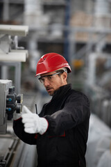 Portrait of worker in factory. Young man with helmet working in factory..