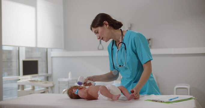 Doctor measuring temperature of little baby with non-contact thermometer in clinic