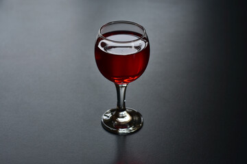 Glass of red wine on a dark background.