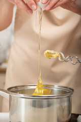 Dough preparation process. Cook adds eggs to the pot.